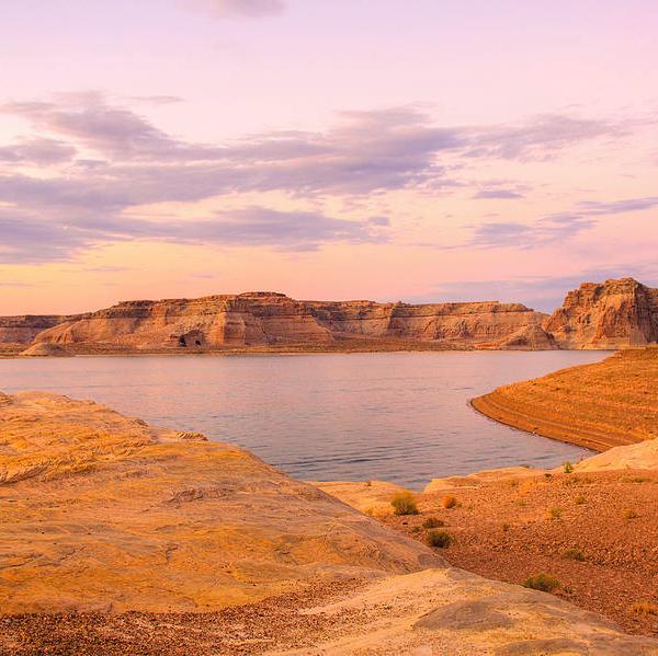 Sunset view over a tranquil lake with surrounding rock cliffs.