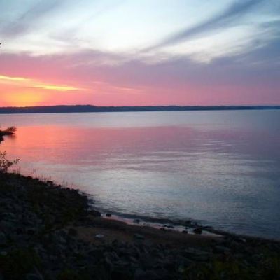 Sunset over a tranquil lake with purple and orange sky.