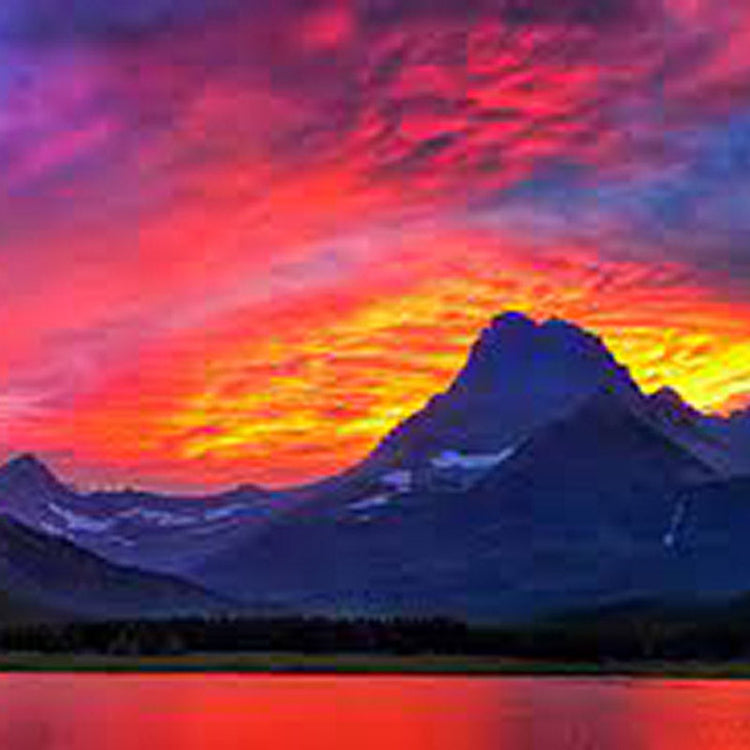 Vibrant sunset with red and pink clouds over a mountain and reflective lake.