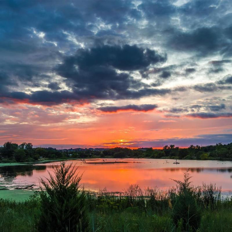 Sunset over a tranquil lake with colorful sky and clouds.