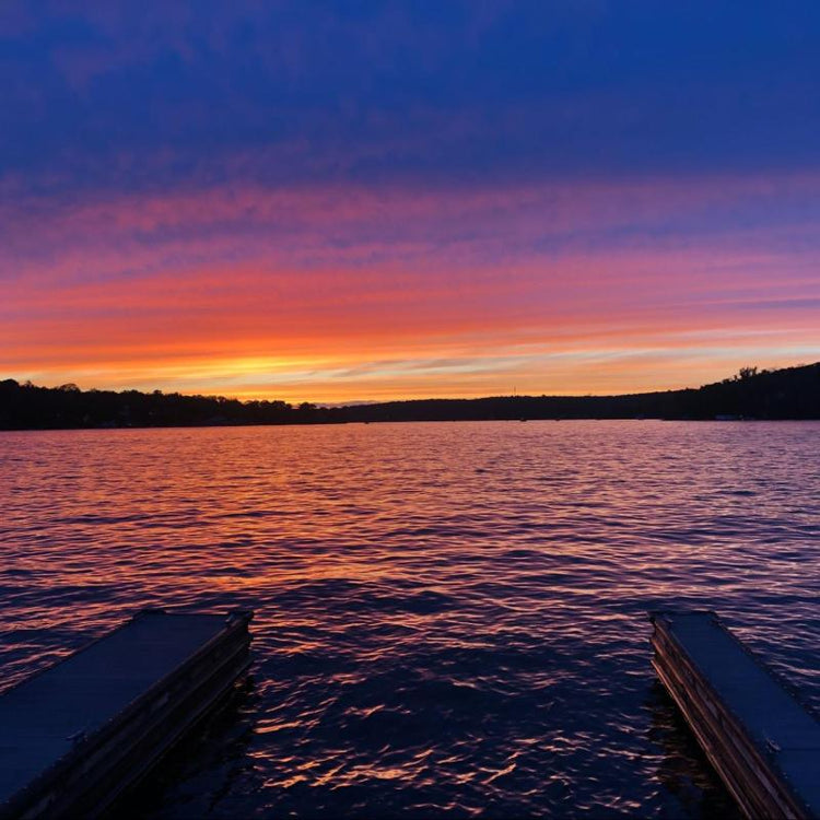 Vibrant sunrise over a tranquil lake with silhouetted trees and docks