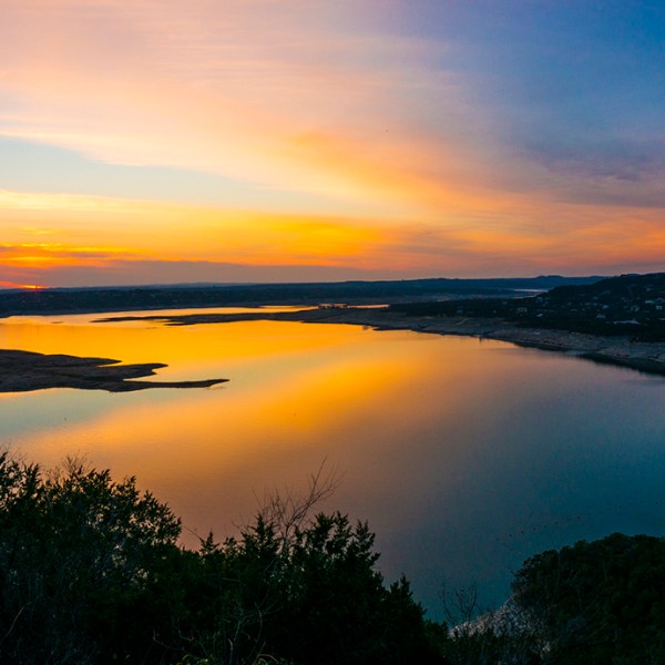 Sunset over a calm lake with reflections of warm sky colors.