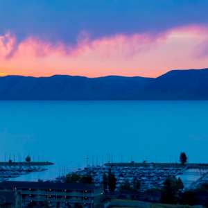 Twilight over a marina with silhouetted mountains and colorful sky.