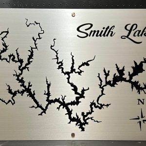 Smith Lake metal map with intricate cutout design and compass rose, mounted on a black pegboard.