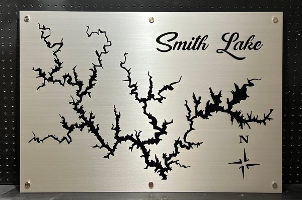 Smith Lake metal map with intricate cutout design and compass rose, mounted on a black pegboard.