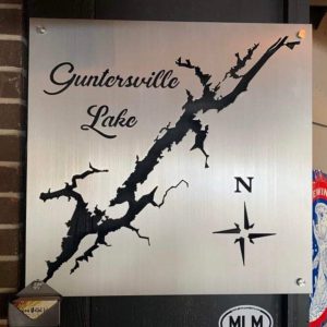 Guntersville Lake metal map with compass design, mounted on a brick wall.