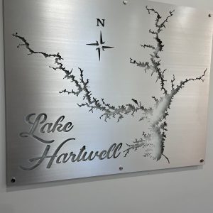 Lake Hartwell map cutout on brushed metal sign with decorative text and compass rose.