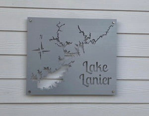 Metal sign of Lake Lanier map with compass rose, mounted on a white wooden wall.