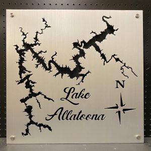 Metal map of Lake Allatoona with compass design, mounted on a perforated black background.