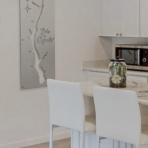 Lake Eufaula map on brushed metal, mounted in a modern kitchen with white decor and a floral centerpiece on the counter.