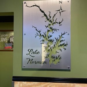 Lake Norman metal map sign with compass rose, mounted on a green wall.