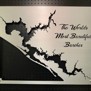 Metal sign with "The World's Most Beautiful Beaches" text and cutout design, mounted on a black pegboard.