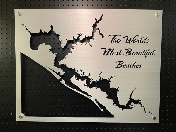 Metal sign with "The World's Most Beautiful Beaches" text and cutout design, mounted on a black pegboard.