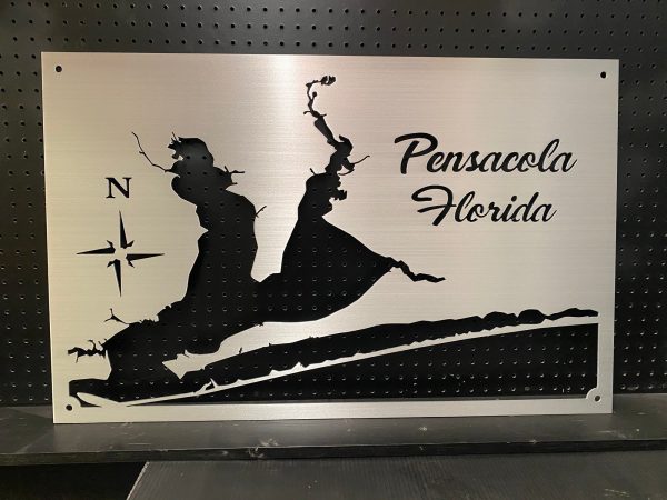 Pensacola Florida metal map with compass rose design, mounted on a black pegboard.