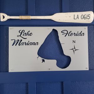 Lake Mariana, Florida custom metal map with compass rose, mounted on a blue wall beneath a decorative oar labeled "LA 0615."