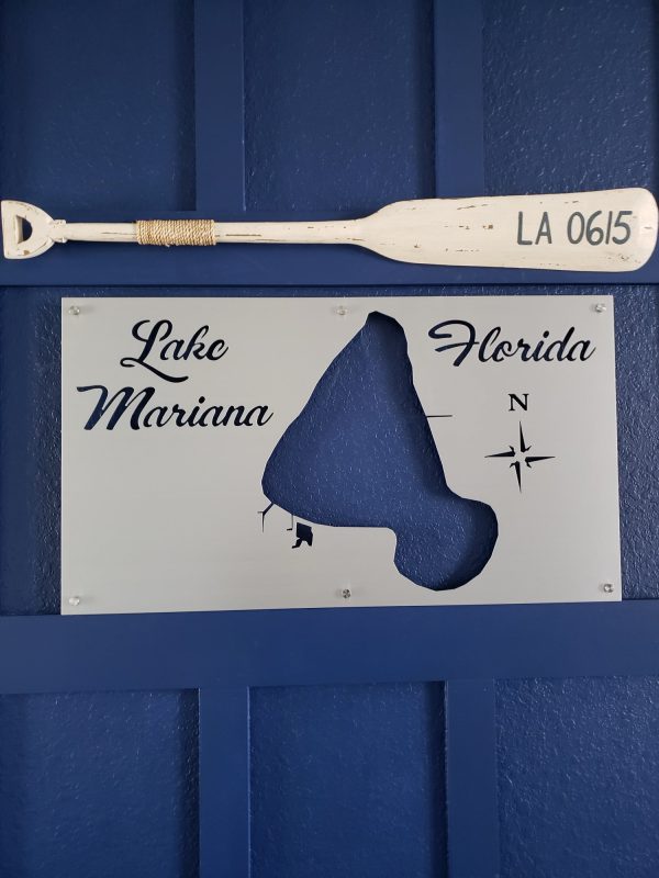 Lake Mariana, Florida custom metal map with compass rose, mounted on a blue wall beneath a decorative oar labeled "LA 0615."