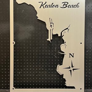 Metal map of Keaton Beach with compass design, mounted on a perforated black background.