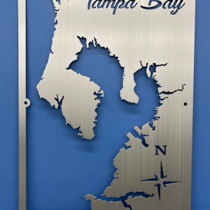 Tampa Bay metal map with compass rose, featuring intricate cutout design, mounted on a blue wall.