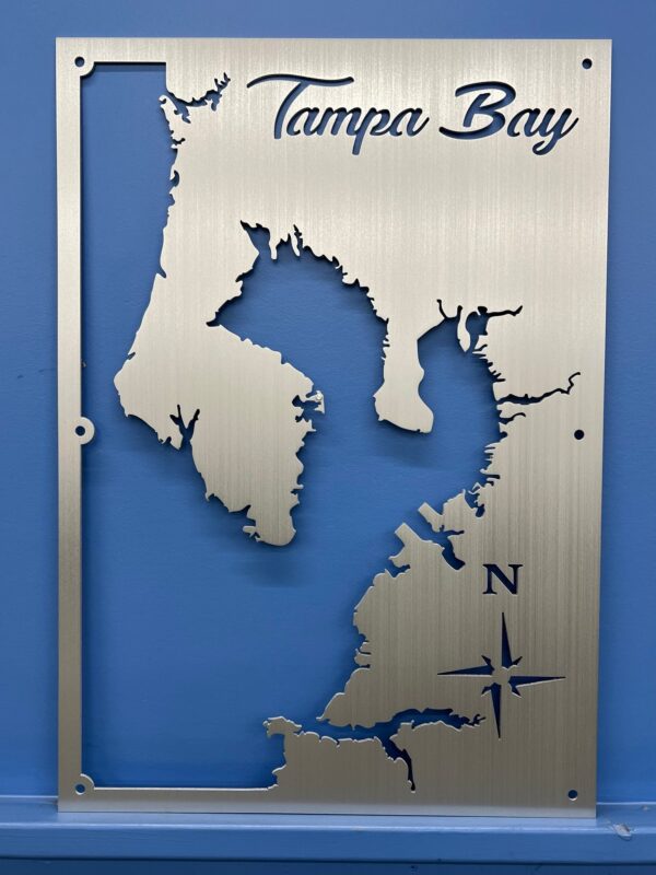 Tampa Bay metal map with compass rose, featuring intricate cutout design, mounted on a blue wall.