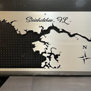 Steinhatchee, FL metal map with compass rose, featuring intricate cutout design on a black pegboard background.