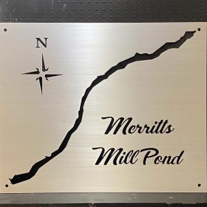 Merritts Mill Pond metal map with compass rose, mounted on a black pegboard background.