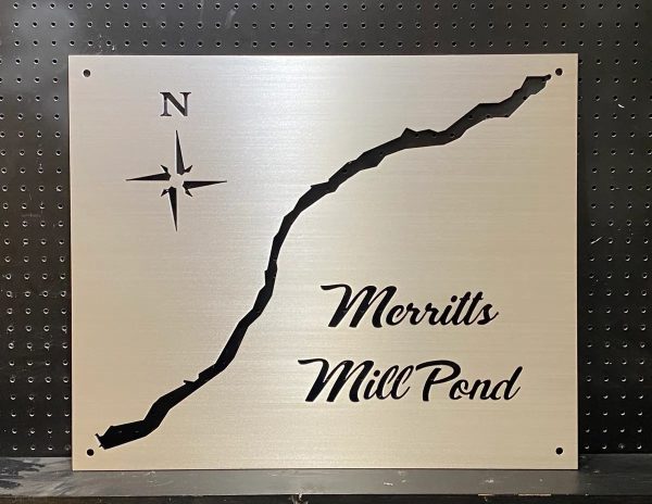 Merritts Mill Pond metal map with compass rose, mounted on a black pegboard background.