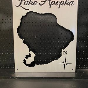 Metal map of Lake Apopka with compass rose design, mounted on a perforated black background.