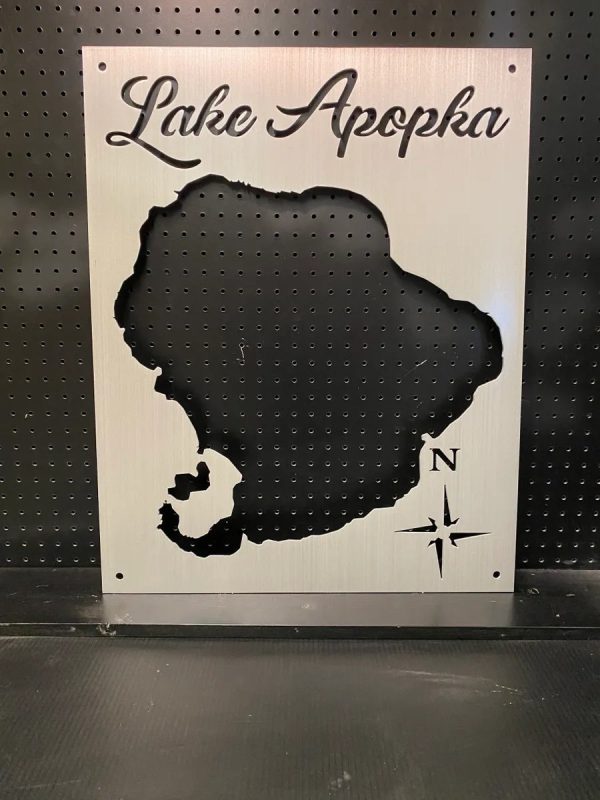 Metal map of Lake Apopka with compass rose design, mounted on a perforated black background.