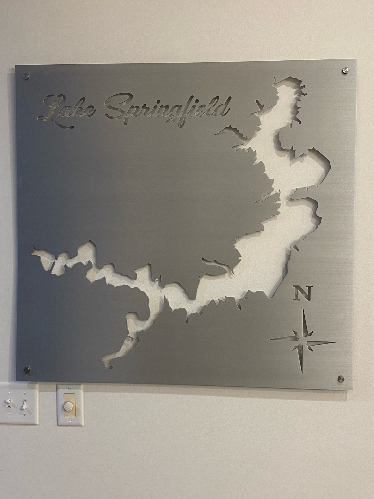 Lake Springfield metal map with compass rose cutout, mounted on a light wall.