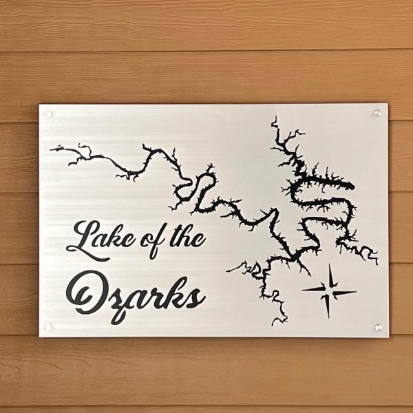 Lake of the Ozarks map sign with compass rose on brushed metal, mounted on a wooden wall.