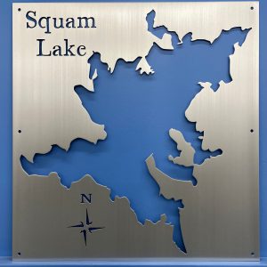 Squam Lake metal map with cutout design and compass rose, mounted on a blue wall.