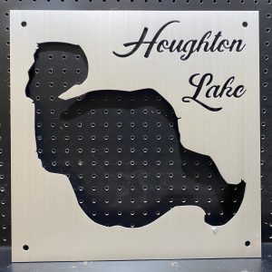 Metal map of Houghton Lake with cutout design on a perforated black background.