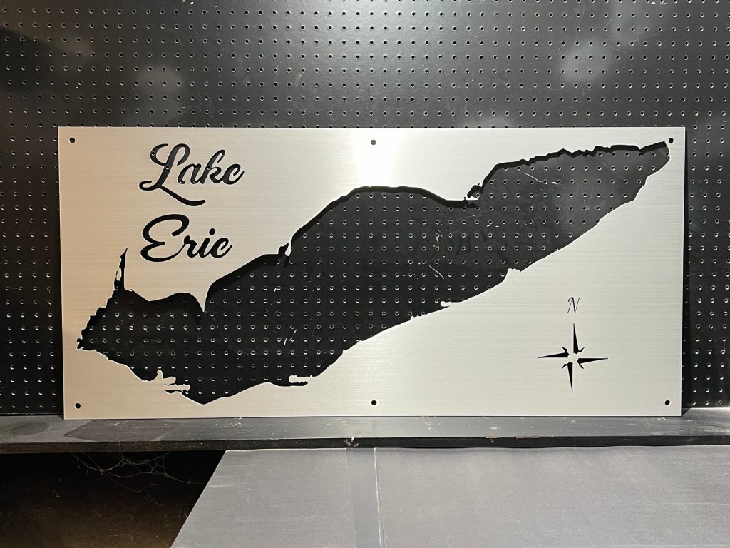 Lake Eric custom metal sign with map cutout and compass rose, mounted on a perforated background.