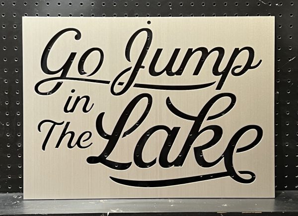 "Go Jump in The Lake" text on a custom metal sign with decorative script against a dotted background.