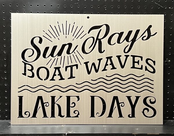 "Sun Rays, Boat Waves, Lake Days" text on brushed metal sign with wave and sunbeam design against perforated background.