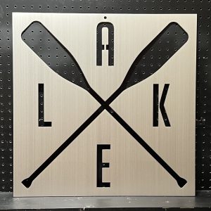 Custom metal sign with crossed oars and "LAKE" cutout on a brushed metallic background.