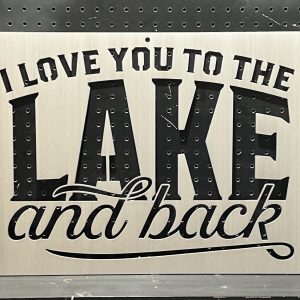 Metal sign with "I Love You to the Lake and Back" text cutout on a perforated background.