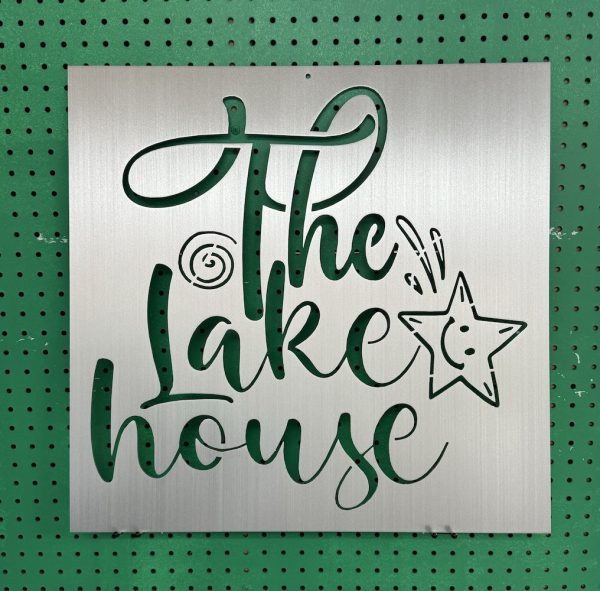 Metal sign with "The Lake House" text and star design on a green pegboard background.