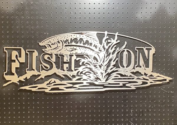 Metal sign with "Fish On" text and a fish jumping out of water, set against a perforated backdrop.