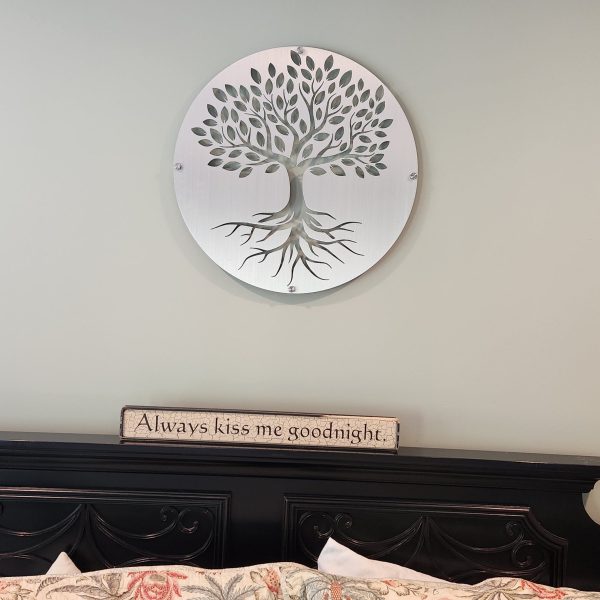 Tree of Life metal art above a bed with "Always kiss me goodnight" sign on the headboard.