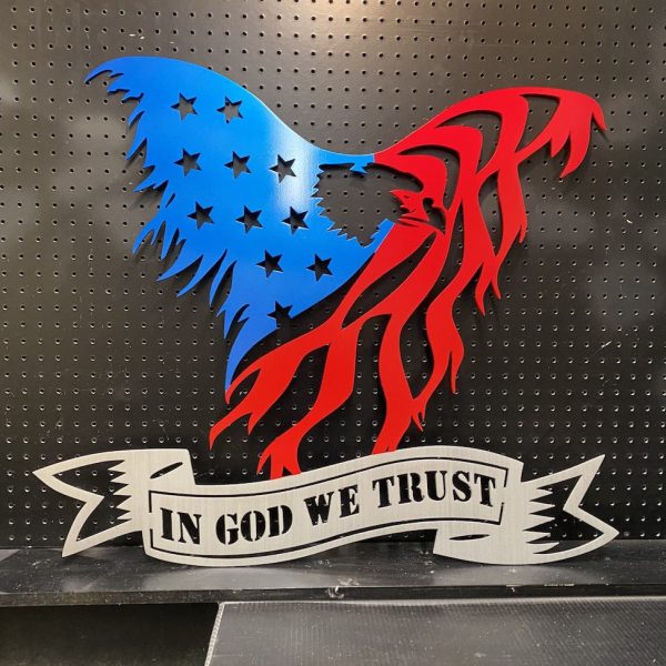 Metal eagle design with stars and stripes in red and blue, featuring "In God We Trust" text on a black pegboard.