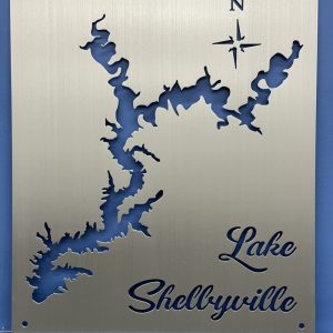 Lake Shelbyville cutout metal map with compass rose on brushed silver, mounted on a blue wall.