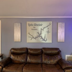 Lake Sinclair map with "The Womac's" text and compass rose, mounted above a leather sofa in a cozy living room.