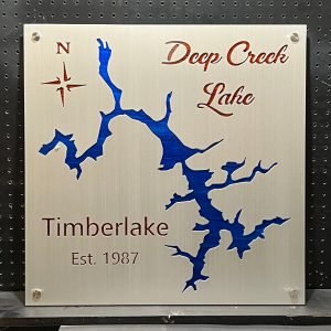 Deep Creek Lake metal map, "Timberlake Est. 1987," with compass rose, mounted on a perforated black background.