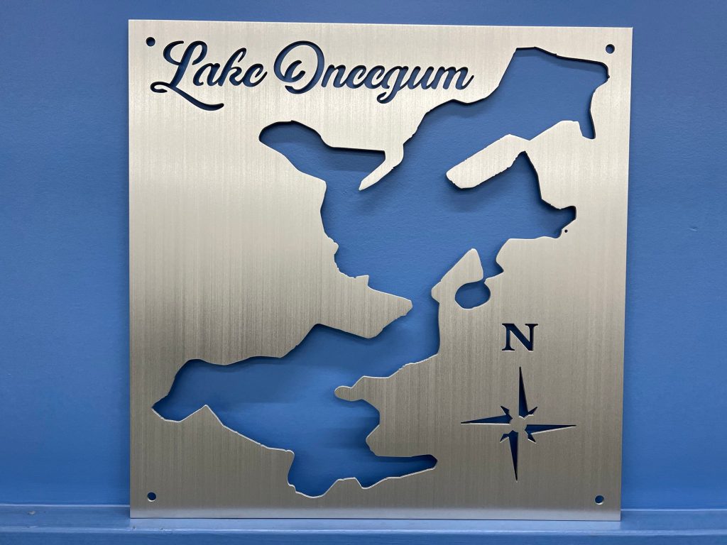 Lake Oneegum metal map with compass rose on brushed silver, mounted on a blue wall.