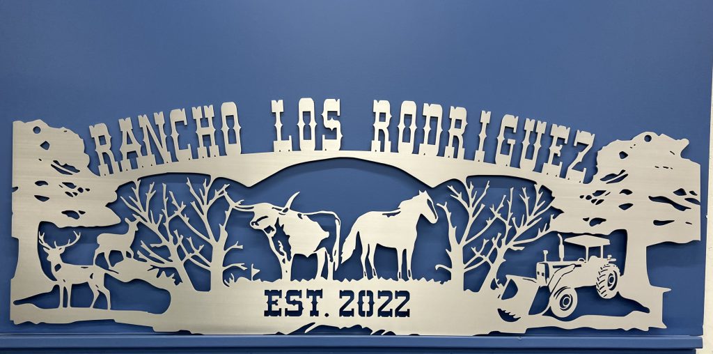 Custom metal ranch sign reading "Rancho Los Rodriguez" with wildlife and tractor, established 2022.