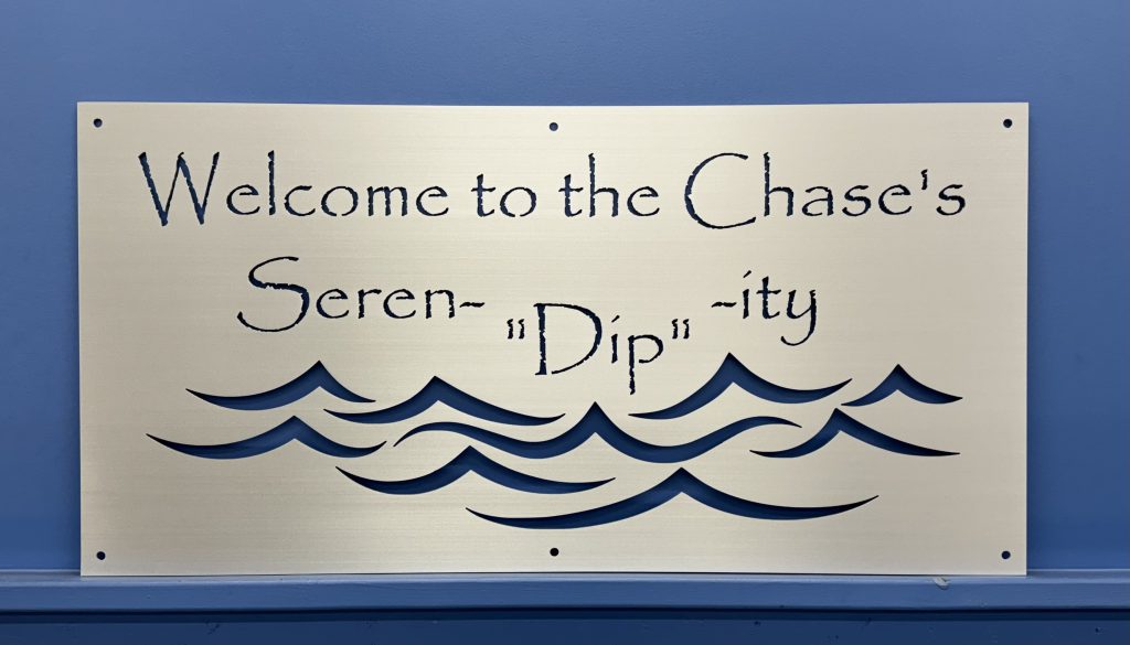 Custom lakehouse sign with "Welcome to the Chase's Seren-'Dip'-ity" text and wave design on a blue wall.