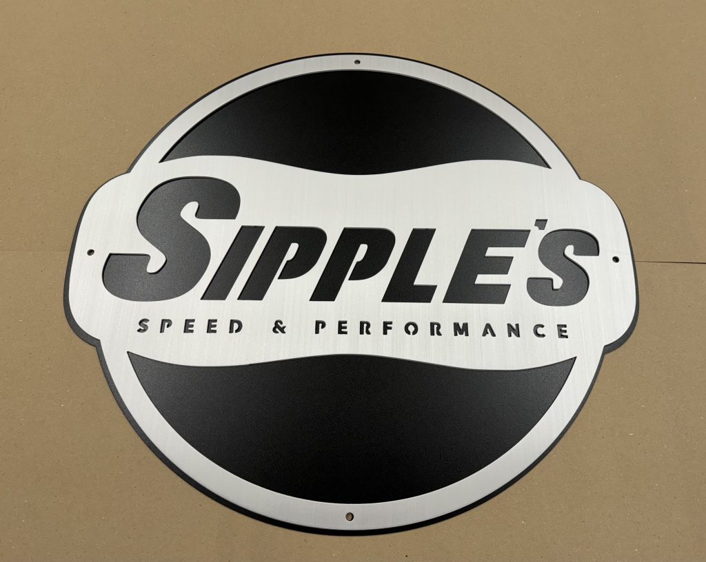 Sipple's Speed & Performance logo on a round metal sign with a black and silver design, placed on a beige background.