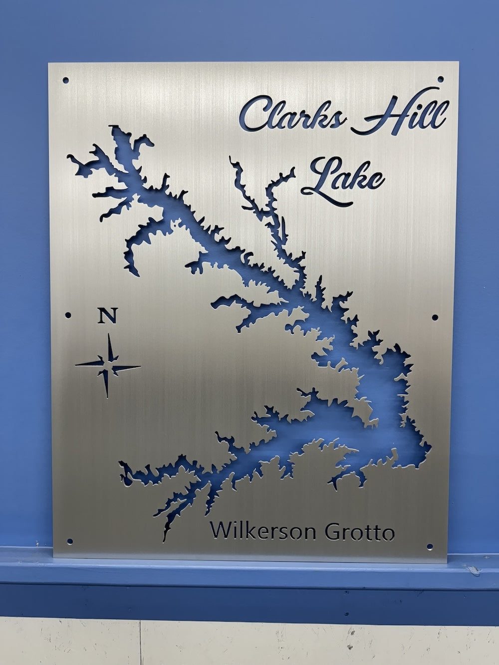 Clarks Hill Lake custom metal map with "Wilkerson Grotto" inscription and compass rose on a blue wall.