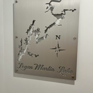 Metal map sign of Logan Martin Lake with compass design on a brushed background, mounted on a wall.